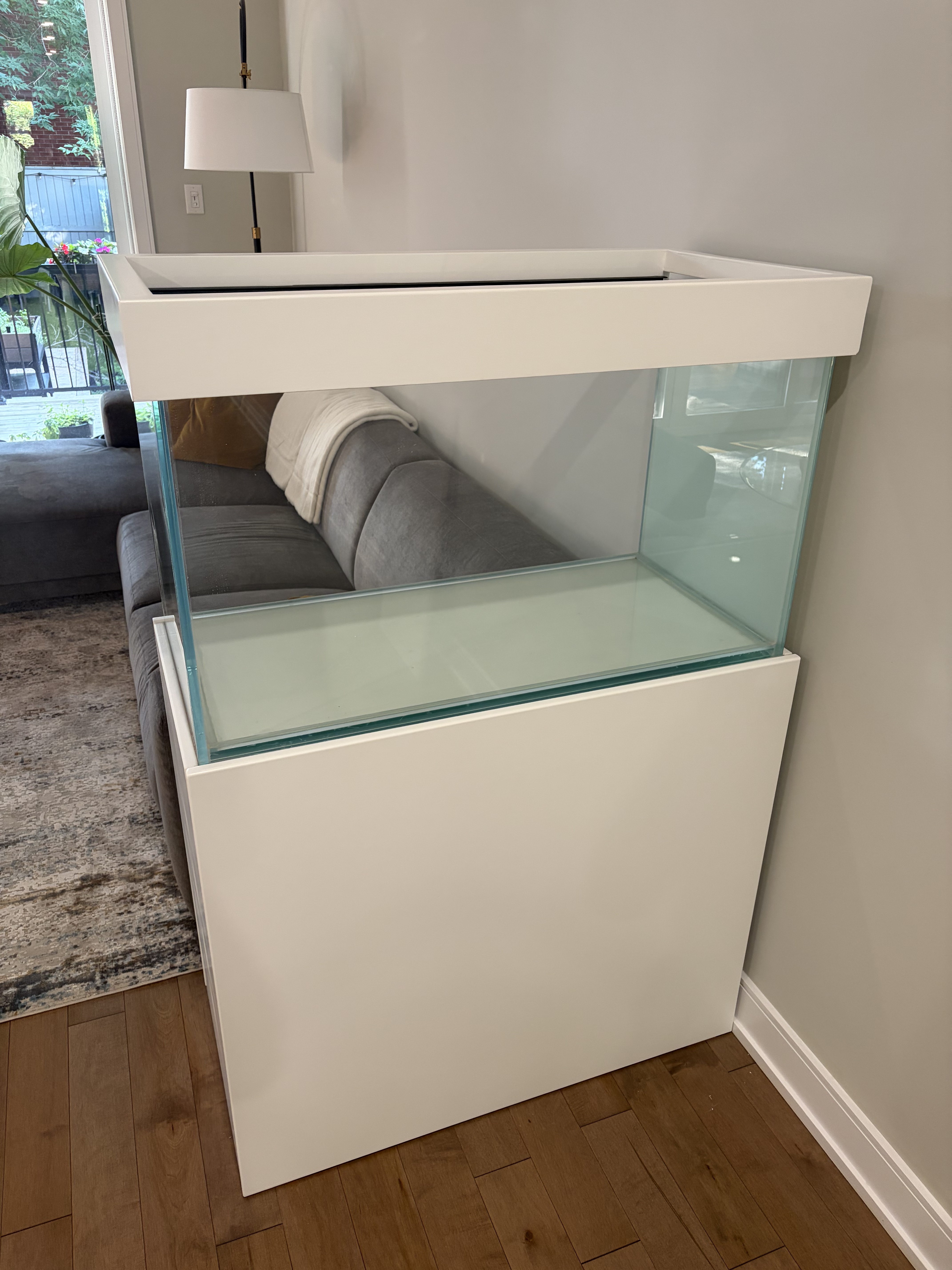 Aquarium specialist standing in front of a custom saltwater reef aquarium installed in a residential home.